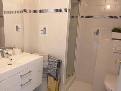 La salle de bains blanche est pourvue d'une douche et d'un lavabo. dans l'établissement Duplex de la Croix Paqueray avec vue mer - Chez Hélène - Gîtes en baie, à Carolles