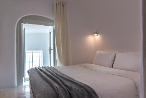 a bedroom with a large white bed with a window at Nefeles Luxury Suites in Fira