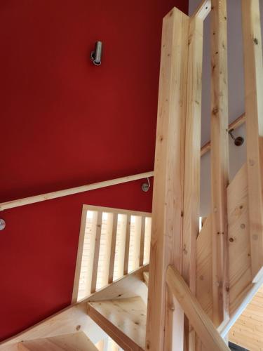 a wooden staircase in a room with a red wall at Gites Jura Sud in Charchilla