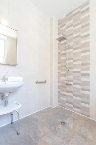 a white bathroom with a sink and a shower at Hostal El Perelló, Valencia in El Perelló
