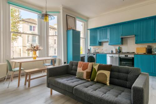 a living room with a couch and a kitchen with blue cabinets at Newly Renovated Central Modern Apartment in Brighton & Hove