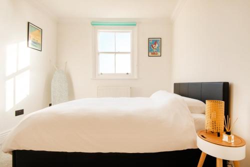 ein weißes Schlafzimmer mit einem großen Bett und einem Tisch in der Unterkunft Newly Renovated Central Modern Apartment in Brighton & Hove