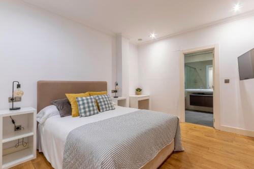 a white bedroom with a bed and a bathroom at Azkuna Comfort Bilbao in Bilbao