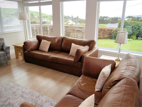 a living room with a brown leather couch and windows at Firpoint in Rockcliffe