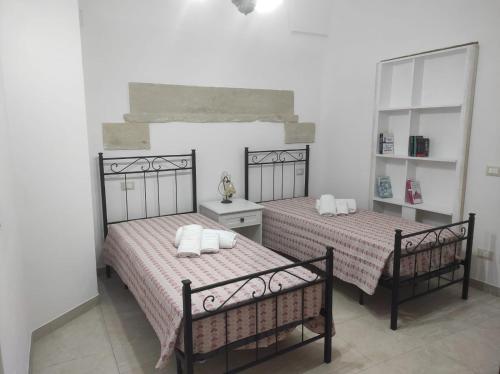 twee bedden in een witte kamer met twee spiegels bij Casa Cesira in Casamassella