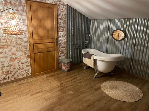 een badkamer met een bad en een houten vloer bij Chez Iréne in Villiers-aux-Chênes
