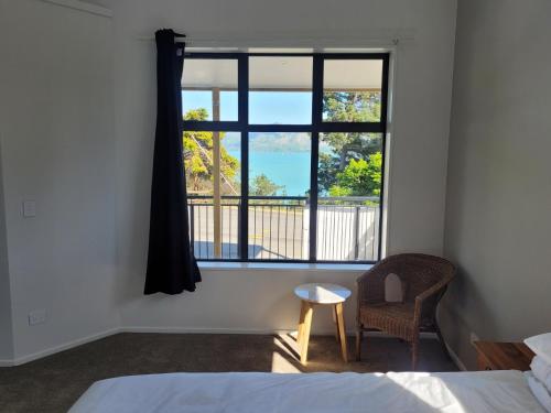 a bedroom with a bed and a window with a chair at Taimana Boutique Motel in Diamond Harbour