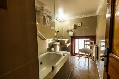 y baño con bañera, lavamanos y silla. en Gervasoni Hotel Boutique, en Valparaíso