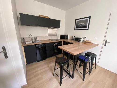 a kitchen with a wooden table and some stools at Le Côté Cour in Barcelonnette