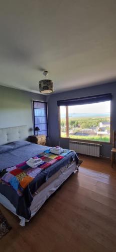 Un dormitorio con una cama y una ventana grande. en Casa Franca, en El Calafate