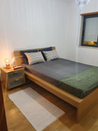 a bedroom with a large bed with a nightstand and a window at Apartamento do Paço do Lumiar in Lisbon