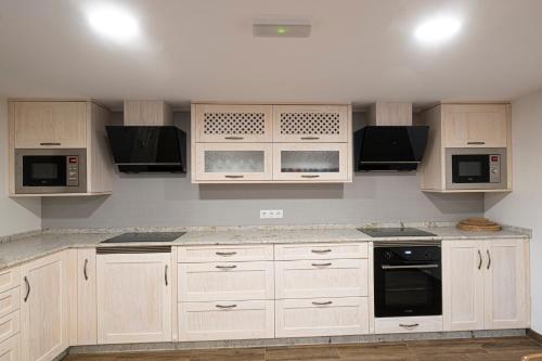 a kitchen with white cabinets and black appliances at Casa Rural Laxido in Rianjo