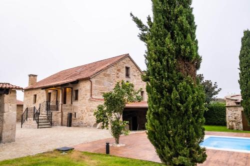an old stone house with a pool and a tree at Casa Rural Laxido in Rianjo