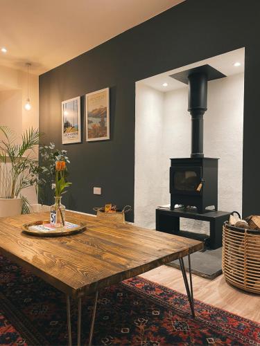 a living room with a wooden table and a stove at The Trossachs Collection in Kepculloch