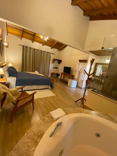 a large bathroom with a tub and a bedroom at Pousada Lua Clara in Alto Paraíso de Goiás