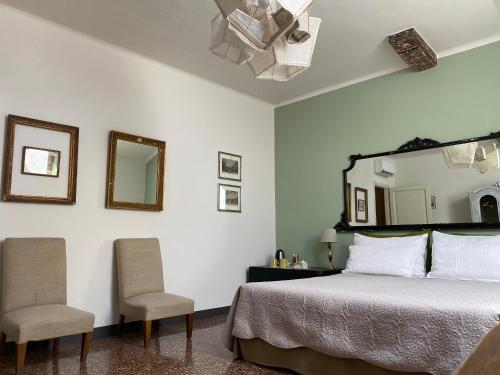 een slaapkamer met een bed met 2 stoelen en een spiegel bij BLQ 01boutique B&B in Bologna