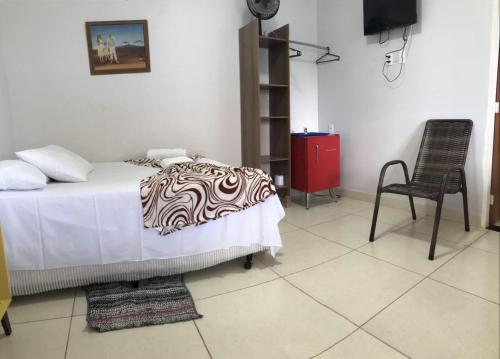 a bedroom with a bed and a chair and a television at Pousada Trilha do Sol in Pirenópolis