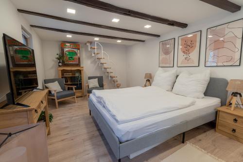 a bedroom with a large white bed and a staircase at Charmantes denkmalgeschütztes Tiny House am Rhein in Rhens