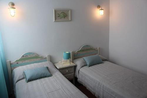 two twin beds in a room with two lamps at Precioso apartamento en complejo con piscina in Cala'n Bosch