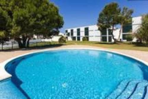 une grande piscine bleue en face d'un bâtiment dans l'établissement Precioso apartamento en complejo con piscina, à Cala'n Bosch