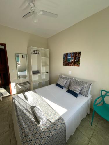 een slaapkamer met een groot wit bed en een ventilator bij Pousada Serrate in Ubatuba