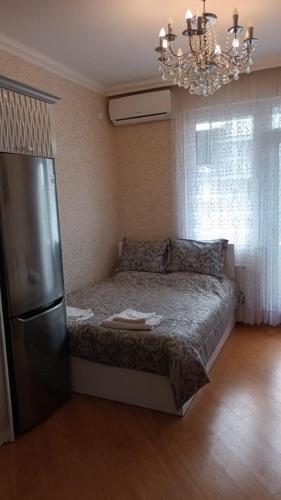 - une chambre avec un lit, un réfrigérateur et un lustre dans l'établissement Gold Baku, à Baku
