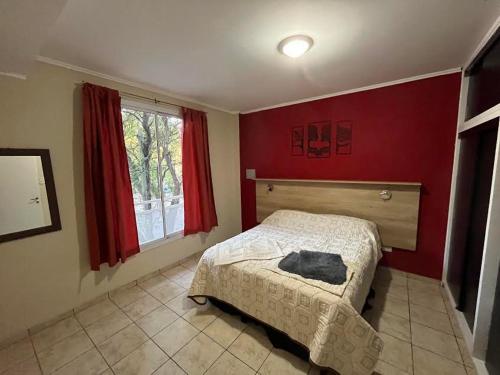 1 dormitorio con cama y pared roja en Departamentos San Rafael Ahora en San Rafael