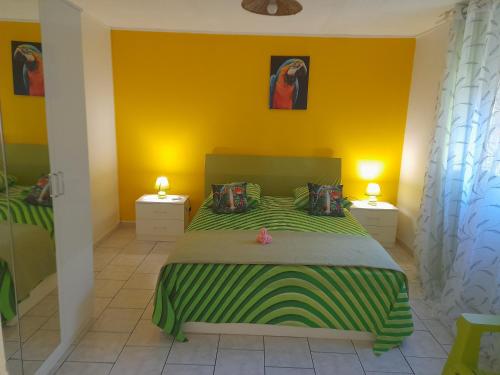 a bedroom with a bed with a green and yellow wall at Villa Campêche in Bouillante
