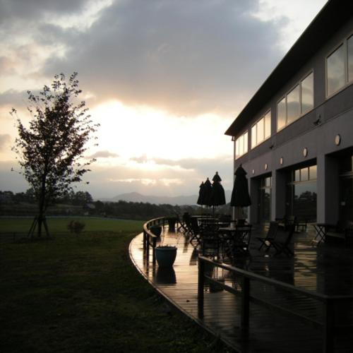 a building with a deck with tables and chairs at Kyukamura Hiruzen-Kogen in Maniwa