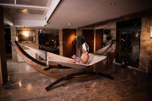 a woman sitting in a hammock in a room at Hotel Borovi Forest Resort & Spa in Sjenica