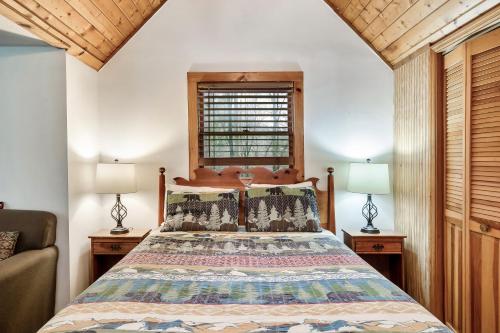 a bedroom with a bed and two lamps and a window at Wolf Run Gatlinburg Location Log Cabin Hot Tub in Gatlinburg