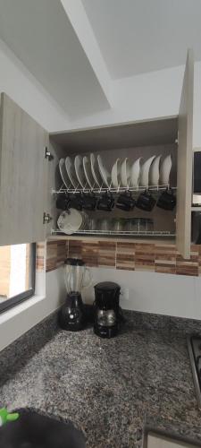 a kitchen counter with plates and bowls on a shelf at Apartamento de verano cerca al parque del café in La Tebaida