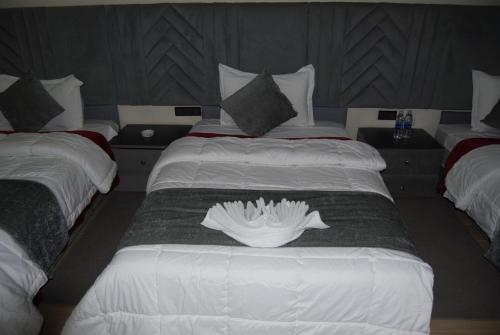 a hotel room with two beds with white sheets at Hotel la Perle d'Arfoud in Erfoud