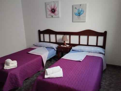 2 łóżka w pokoju z fioletową pościelą i ręcznikami w obiekcie Los Camarones w mieście La Restinga