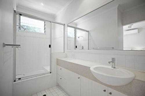a white bathroom with a sink and a shower at 2 Casuarinas Peregian Beach in Coolum Beach