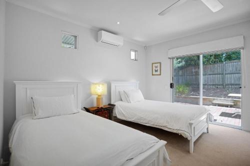 two beds in a white room with a window at 2 Casuarinas Peregian Beach in Coolum Beach