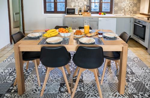 einen Holztisch mit Stühlen und Obst darauf in der Küche in der Unterkunft Au cœur de joigny in Joigny