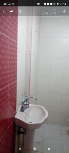 La salle de bains est pourvue d'un lavabo et d'un mur rouge et blanc. dans l'établissement شقة مفروشة مجهزة للطلبة و الموظفين, au Caire