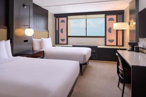 una camera d'albergo con 2 letti e una scrivania di Hotel Renew a Honolulu