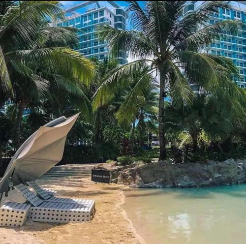 a beach with a chair and an umbrella and palm trees at AZURE Urban Resort Residences Condominium in Manila