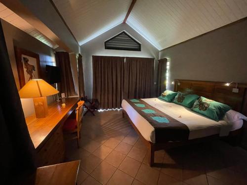 a bedroom with a bed and a desk with a lamp at Tiki Hôtel - Hôtel d'application du Lycée de Tahiti in Punaauia