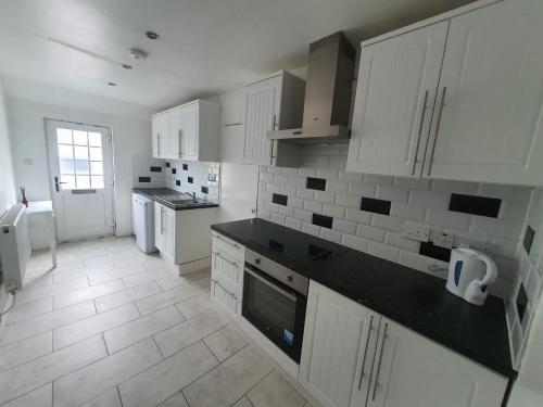 a kitchen with white cabinets and a black counter top at Chantilly in Ickenham