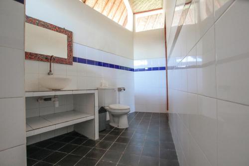 a bathroom with a toilet and a sink and a window at Ganesha Amed in Amed