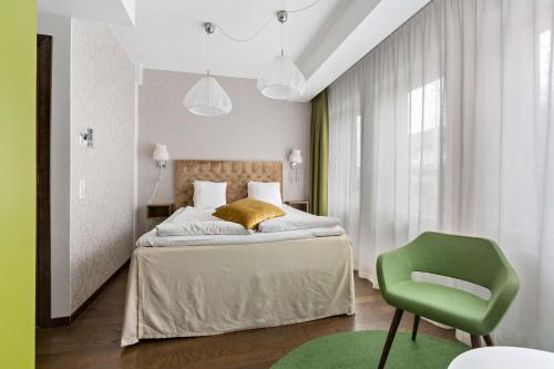 a bedroom with a bed and a green chair at Best Western The Public Hotel in Åkersberga