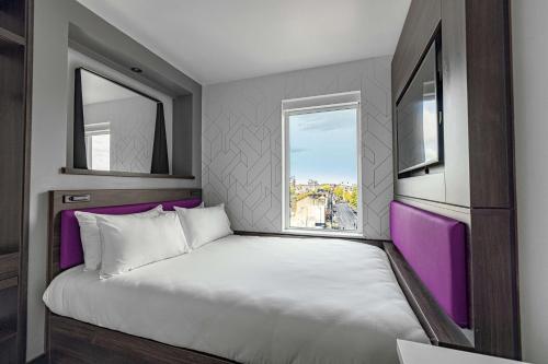 um quarto com uma cama grande e 2 janelas em YOTEL London Shoreditch em Londres