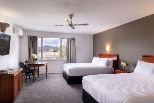 um quarto de hotel com duas camas e uma mesa e uma janela em Arawa Park Hotel, Independent Collection by EVT em Rotorua