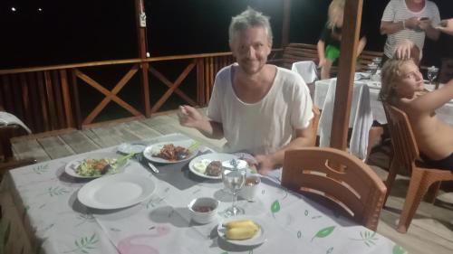 a man and a child sitting at a table with food at Yohana Cottage in Tual