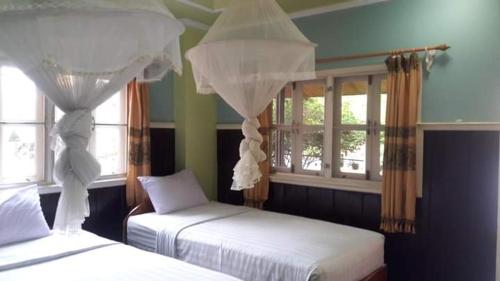 a bedroom with two beds and two windows at Pan guest house in Ban Donsôm