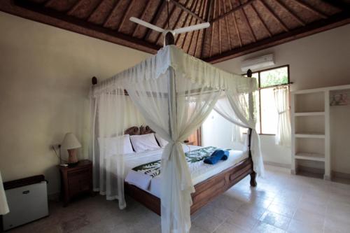 a bedroom with a canopy bed with a mosquito net at Ganesha Amed in Amed