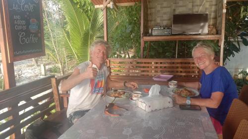 two men sitting at a table eating food at Yohana Cottage in Tual